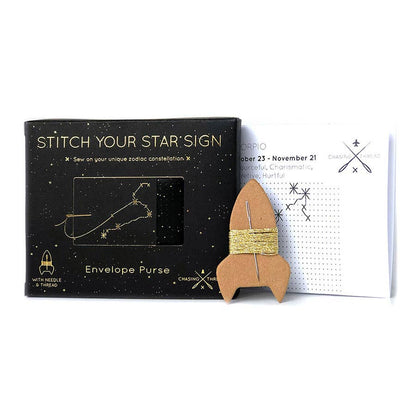 A Stitch Your Star Sign craft kit by Chosen Thread, featuring a black starry-themed box, a white instruction sheet, and a wooden rocket-shaped envelope purse wrapped in gold thread.