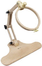A wooden adjustable embroidery hoop stand with a curved base, articulated arms, and a light natural wood hoop, shown on a plain white background.