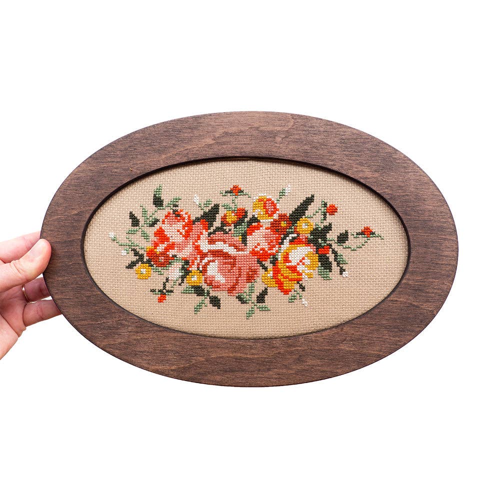 Oval wooden frame with floral embroidery on a white background