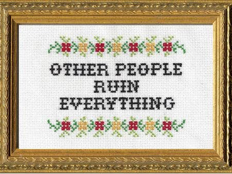 Cross-stitched text with decorative border in a gold frame