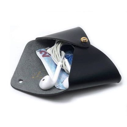 A black leather earbud pouch shown open on a white background, containing white earbuds and a blue banknote.